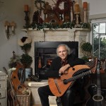 John Doan Victorian Christmas Concert with harp guitar in front of fire place.