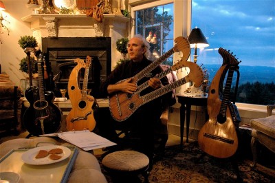 John Doan home concert with various antique harp guitars with the sun setting in the background through the window.